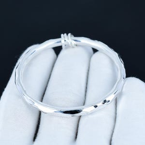 May include: A silver bangle bracelet with a hammered finish and a twisted wire clasp.