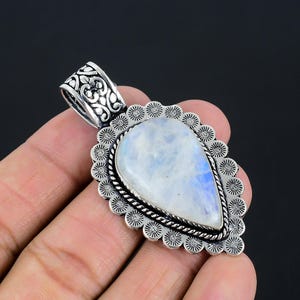 May include: A silver pendant featuring a teardrop-shaped moonstone set within an intricate filigree design.