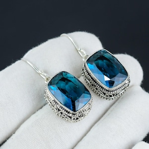 May include: A pair of silver dangle earrings with a large, rectangular, blue gemstone set in a filigree design.