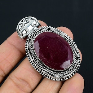 以下が含まれることがあります： 装飾的な銀の枠にセットされた、大きな楕円形の濃い紫色の宝石が付いた銀のペンダント