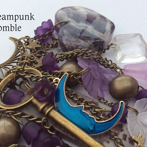 Pu&ograve; includere: Un braccialetto con ciondoli a tema steampunk con una chiave, ciondoli a forma di luna, fiori viola e una grande pietra di ametista.