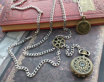 May include: A silver chain necklace with two antique-style pocket watches. One watch has a gear design and the other has a decorative, open-faced design.