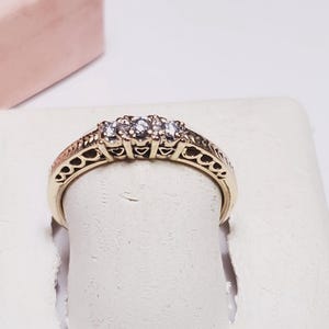 May include: A gold ring with a delicate filigree design and three small diamonds.