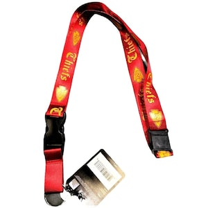 May include: Red lanyard with gold lettering and a logo that says "Chiefs" and a gold arrow. The lanyard has a black clip on each end.
