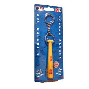 May include: A yellow baseball bat-shaped bottle opener keychain with a silver chain and ring. The keychain is on a blue card with the text "BAT KEYCHAIN BOTTLE OPENER". The baseball team logo is visible.