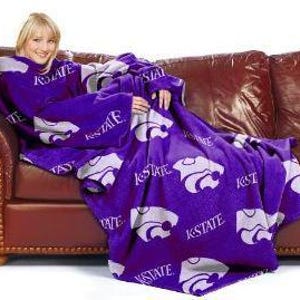 May include: Purple fleece blanket with a large white K-State Wildcat logo and the words "K-State" repeated throughout. The blanket has sleeves and is designed to be worn like a robe.