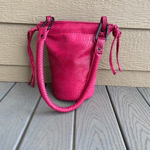 SIDEWINDER- Vinyl faux python bucket bag with rounded shoulder strap and spring links.