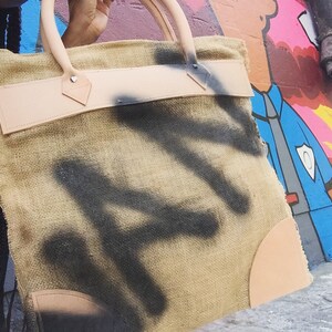 Vandal (Burlap maxi pouch with top stitched leather detail, chunky leather top handles and spray painted graffiti)