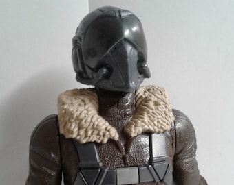 May include: A brown leather jacket with a fur collar and a gray helmet. The jacket has a gray chest harness with straps and buckles. The helmet has a visor and a gray face mask.