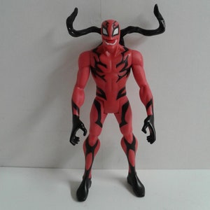 Pode incluir: Figura de a&ccedil;&atilde;o vermelha e preta de um super-her&oacute;i com chifres. A figura tem uma express&atilde;o amea&ccedil;adora e est&aacute; em posi&ccedil;&atilde;o de p&eacute;.