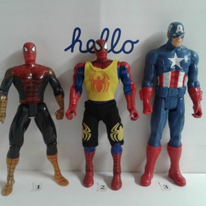 May include: Three action figures, two Spider-Man figures and one Captain America figure. The Spider-Man figures are wearing red and blue suits with a spider logo. The Captain America figure is wearing a blue and red suit with a white star on the chest. The figures are standing on a white surface.