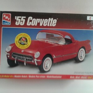 Pu&ograve; includere: Scatola di un modellino di una Corvette '55 rossa. La scatola presenta la scritta "'55 Corvette" e il marchio "AMT". Il modello di auto &egrave; rosso con pneumatici a fascia bianca. Un adesivo giallo recita "50 Years".