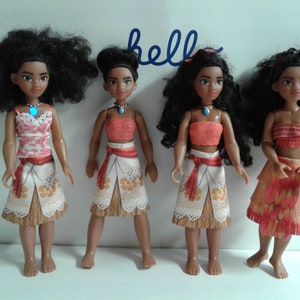 May include: Four Moana dolls with different outfits. The dolls have brown skin, black curly hair, and brown eyes. The dolls are wearing different outfits, including a pink and white top with a white skirt, a red top with a white skirt, a red top with a brown skirt, and a red top with a brown skirt with a red and orange pattern.