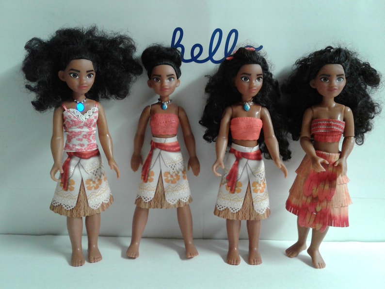 May include: Four Moana dolls with different outfits. The dolls have brown skin, black curly hair, and brown eyes. The dolls are wearing different outfits, including a pink and white top with a white skirt, a red top with a white skirt, a red top with a brown skirt, and a red top with a brown skirt with a red and orange pattern.