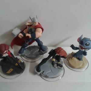 May include: Four Disney Infinity figures: a red and black figure of Black Widow, a blue and red figure of Thor, a blue figure of Stitch, and a red and black figure of Black Widow.