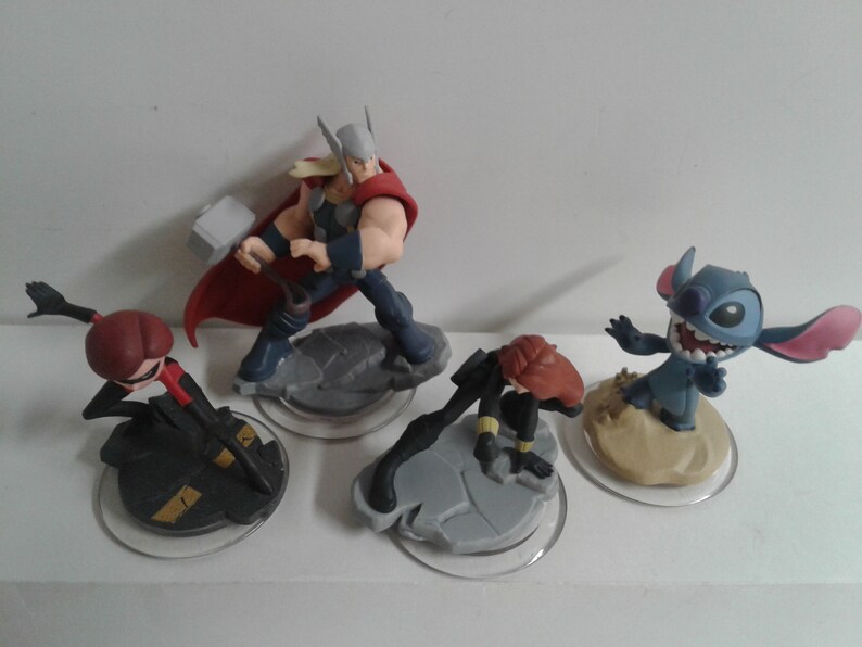 May include: Four Disney Infinity figures: a red and black figure of Black Widow, a blue and red figure of Thor, a blue figure of Stitch, and a red and black figure of Black Widow.