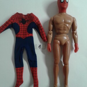 Op de afbeelding: Een vintage action figure van Spider-Man met een rood en blauw pak en een rood masker. De figuur mist zijn armen en benen, maar de romp en het hoofd zijn intact. De figuur staat met zijn armen langs zijn zijde. De figuur staat op een witte achtergrond.