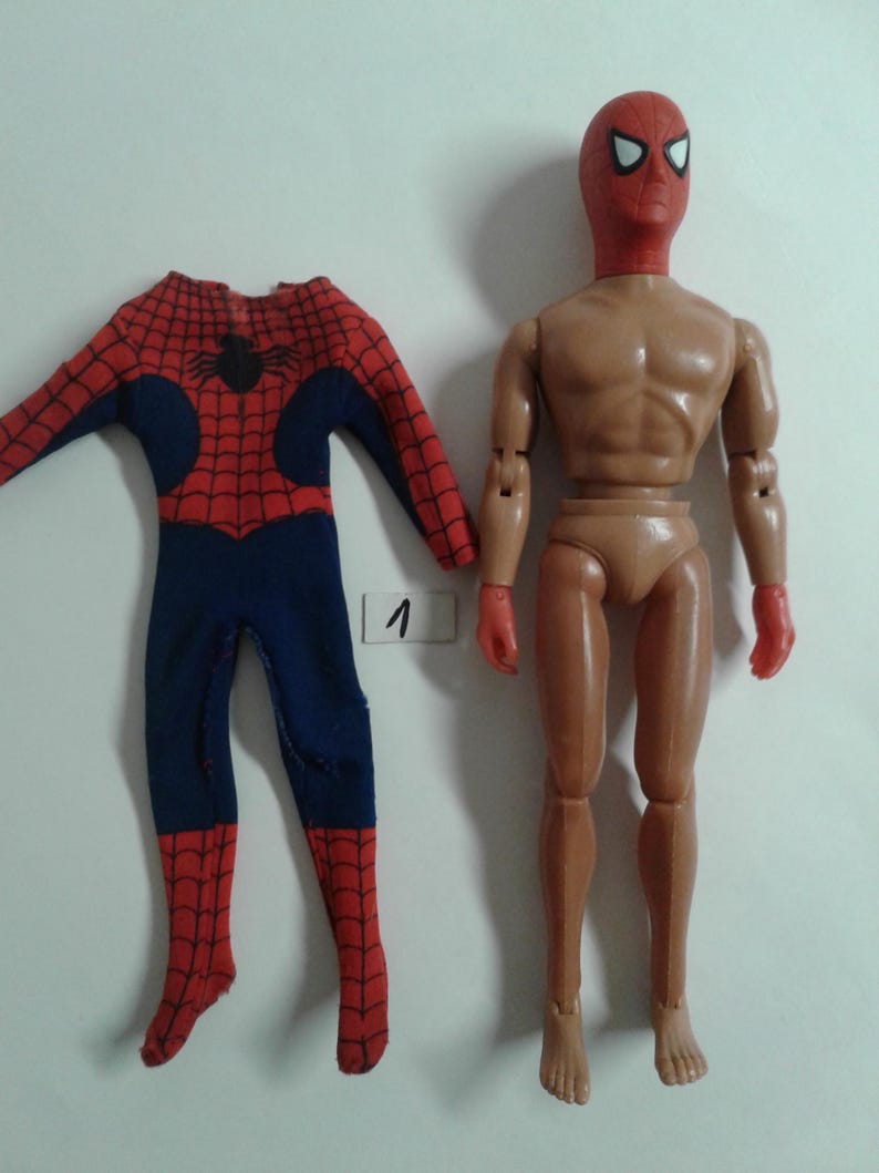 Op de afbeelding: Een vintage action figure van Spider-Man met een rood en blauw pak en een rood masker. De figuur mist zijn armen en benen, maar de romp en het hoofd zijn intact. De figuur staat met zijn armen langs zijn zijde. De figuur staat op een witte achtergrond.
