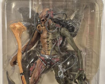 May include: A Todd McFarlane's Spawn Ultra-Action Figure in its original blister packaging. The figure features a skeletal, biomechanical design with exposed wiring, a tan and green textured body, red accents, and a long, bone-like staff accessory.