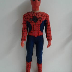 Op de afbeelding: Een rood en blauw Spider-Man-actiefiguur met een spinnenwebontwerp. De figuur heeft een rood masker met witte ogen en een zwarte spin op de borst.