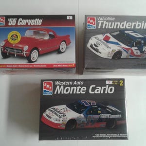 Pu&ograve; includere: Sono esposti tre kit di modellini di auto. La scatola in alto a sinistra presenta una '55 Corvette rossa. La scatola in alto a destra mostra un'auto da corsa Valvoline Thunderbird. La scatola in basso mostra un'auto da corsa Western Auto Monte Carlo.