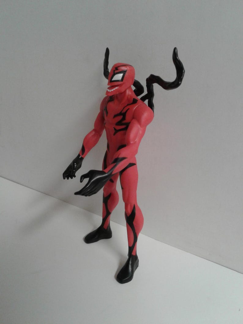 Pode incluir: Figura de a&ccedil;&atilde;o vermelha e preta de um super-her&oacute;i com um traje simbi&oacute;tico. A figura tem uma express&atilde;o amea&ccedil;adora e est&aacute; em pose com os bra&ccedil;os estendidos.