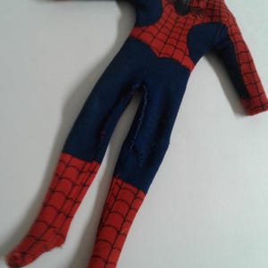 Op de afbeelding: Een rood en blauw Spiderman-kostuum met een spinnenwebontwerp. Het kostuum is gemaakt van stof en heeft lange mouwen en benen.