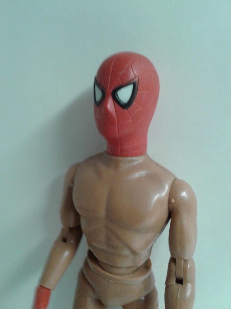 Op de afbeelding: Een rood en zwart plastic actifiguur hoofd met een wit spinnenweb ontwerp. Het hoofd is bevestigd aan een bruin plastic lichaam.