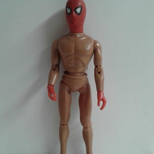 Op de afbeelding: Een naakt action figure met een rood-wit Spider-Man masker.