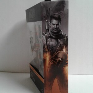 May include: A cardboard box with a Star Wars: The Mandalorian figure inside. The figure is of Cobb Vanth, a character from the show. The box is brown and has a picture of Cobb Vanth on the front. The text "COBB VANTH" is printed on the bottom of the box.