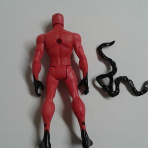 Pode incluir: Figura de a&ccedil;&atilde;o vermelha com detalhes pretos, em p&eacute; com um acess&oacute;rio de cauda preto. A figura tem um furo nas costas.