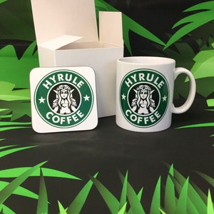 May include: A white mug and a coaster with a green logo that says "Hyrule Coffee" and features a stylized image of a woman with a crown. The mug and coaster are on a green and black background.
