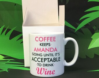 May include: White ceramic coffee mug with a pink and black design. The mug reads "Coffee keeps Amanda going until it's acceptable to drink wine".