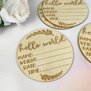 May include: Three round wooden plaques with the text "hello world" and blank lines for "name", "weight", "date", and "time".