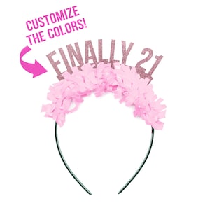 May include: Pink headband with the words "FINALLY 21" in pink glitter letters. The headband is decorated with pink tissue paper streamers. The text "CUSTOMIZE THE COLORS!" is written in pink on a white background.