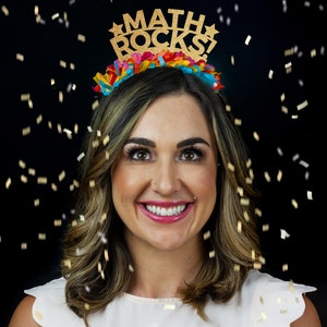 K&ouml;nnte beinhalten: Eine Frau tr&auml;gt ein goldenes Glitzer-Haarband mit dem Text "MATH ROCKS!" darauf. Sie l&auml;chelt und Konfetti f&auml;llt um sie herum.