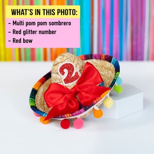 Op de afbeelding: Een kleine, veelkleurige pompon sombrero met een rood glitter nummer "2" en een rode strik.