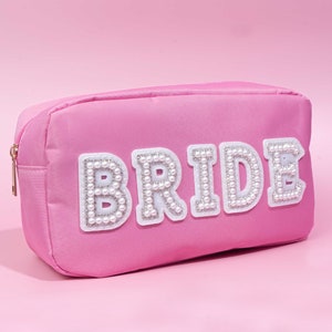 May include: Pink satin cosmetic bag with a white pearl-embellished "BRIDE" design.