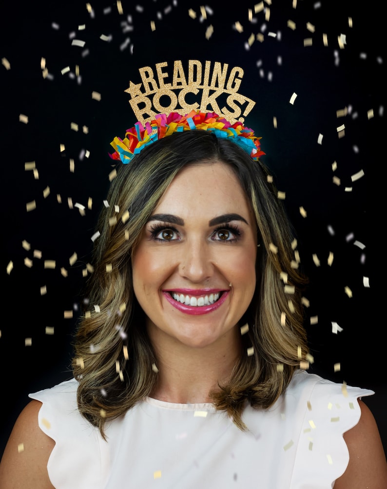 May include: A woman wearing a gold glitter headband with the words "Reading Rocks!" on it. She is smiling and confetti is falling around her.