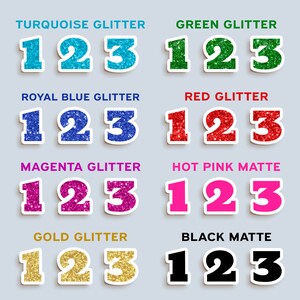 Op de afbeelding: Een set van acht 123-nummer stickers in verschillende kleuren en afwerkingen. De kleuren omvatten turquoise, groen, koninklijk blauw, rood, magenta, roze, goud en zwart. De afwerkingen omvatten glitter en mat.
