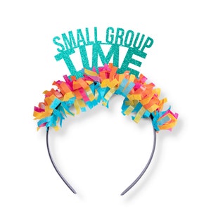 May include: A teal blue headband with the words "Small Group Time" in glitter letters. The headband is decorated with colorful streamers.