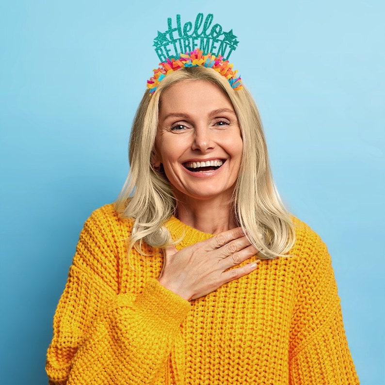 May include: A woman wearing a yellow sweater smiles while wearing a teal blue headband with the text "Hello Retirement" and colorful streamers.