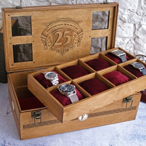 May include: A wooden watch box with a hinged lid and a velvet interior. The lid has a clear glass window and is engraved with the text "Happy Birthday Dear Brother 25". The box has eight compartments for storing watches.