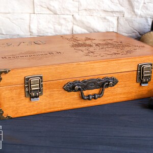 May include: A wooden box with a hinged lid and a metal handle. The box is engraved with the text "12/70 Kalinina K.H.".