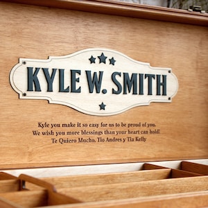 May include: A wooden keepsake box with a personalised engraved plaque that reads "KYLE W. SMITH". The box has a message inscribed on the lid: "Kyle you make it so easy for us to be proud of you. We wish you more blessings than your heart can hold! Te Quiero Mucho, Tio Andres y Tia Kelly".