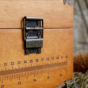 May include: A wooden box with a brass hinge and a ruler printed on the front. The ruler is marked with numbers from 28 to 42.