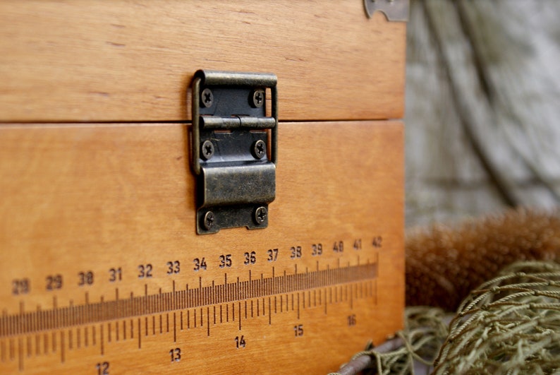 May include: A wooden box with a brass hinge and a ruler printed on the front. The ruler is marked with numbers from 28 to 42.