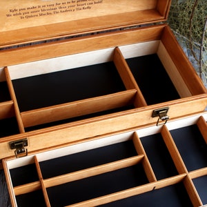 May include: A wooden box with two layers of compartments. The top layer has four compartments and the bottom layer has eight compartments. The box is made of light wood and has a black felt lining. The box is open and the compartments are empty.