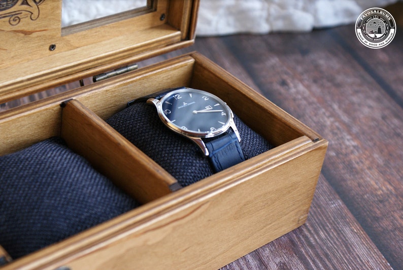 May include: A wooden watch box with a blue velvet interior. A silver watch with a blue face and a blue leather band is resting in the box.