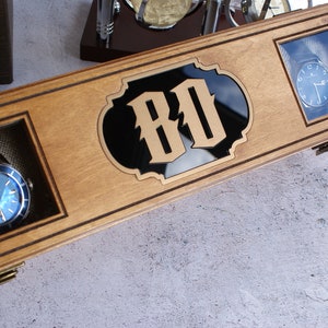 Peut inclure: Une bo&icirc;te &agrave; montres rectangulaire en bois clair, dot&eacute;e de deux fen&ecirc;tres d'affichage en verre et d'une incrustation centrale en acrylique noir portant les lettres dor&eacute;es BD. La bo&icirc;te contient deux montres-bracelets &agrave; cadran bleu.